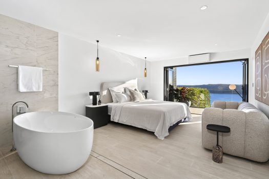 Modern bedroom with ocean view and freestanding bathtub.