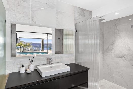 Modern bathroom with view of pool and mountains.